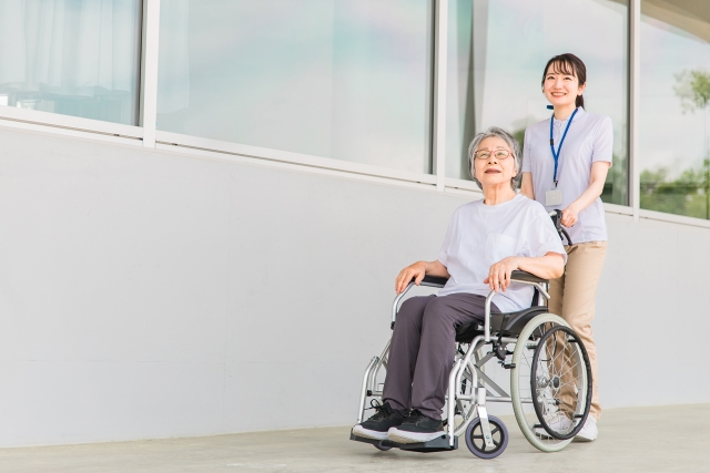 車椅子でお散歩をする女性とスタッフ